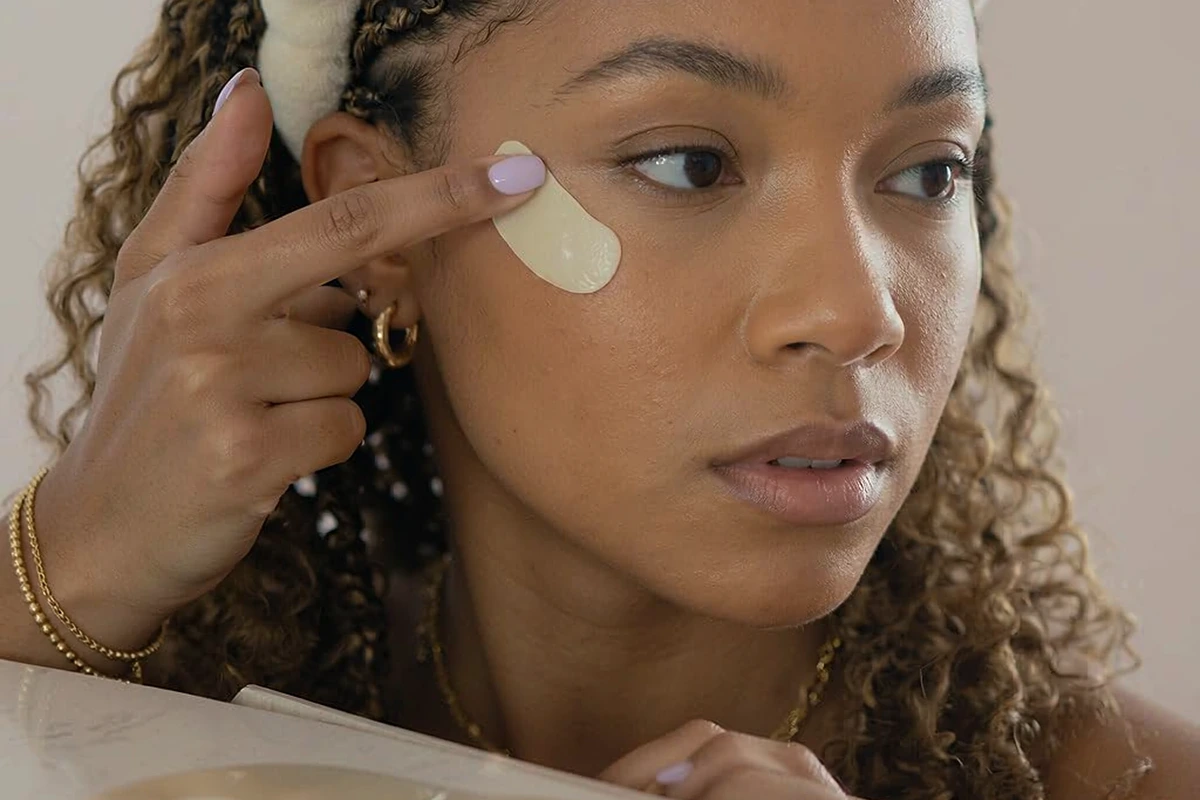 Woman applying a curved under-eye wrinkle patch with her fingertip