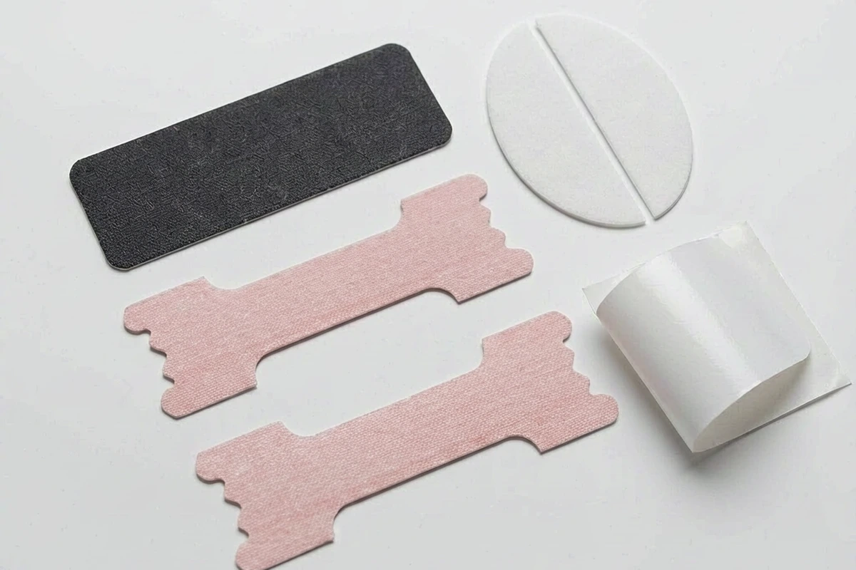 Flat lay of several mouth tape designs including a black strip, a split oval and a pink strip with release liner